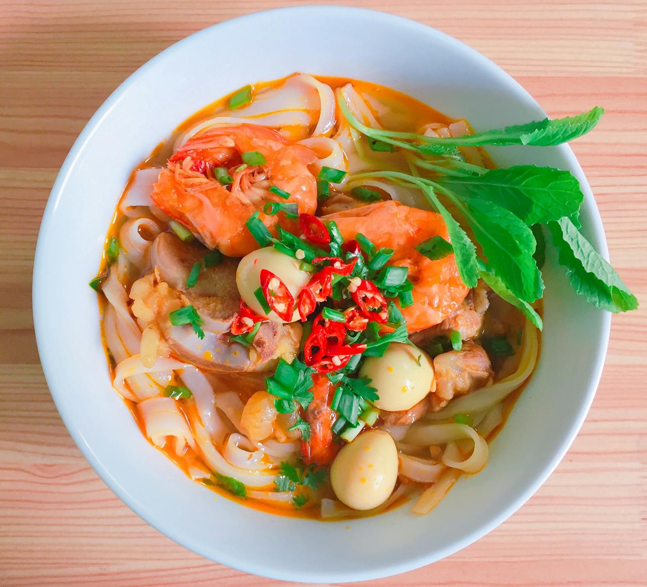 our-services-05 A vibrant bowl of Vietnamese noodle soup with shrimp, herbs, and quail eggs.